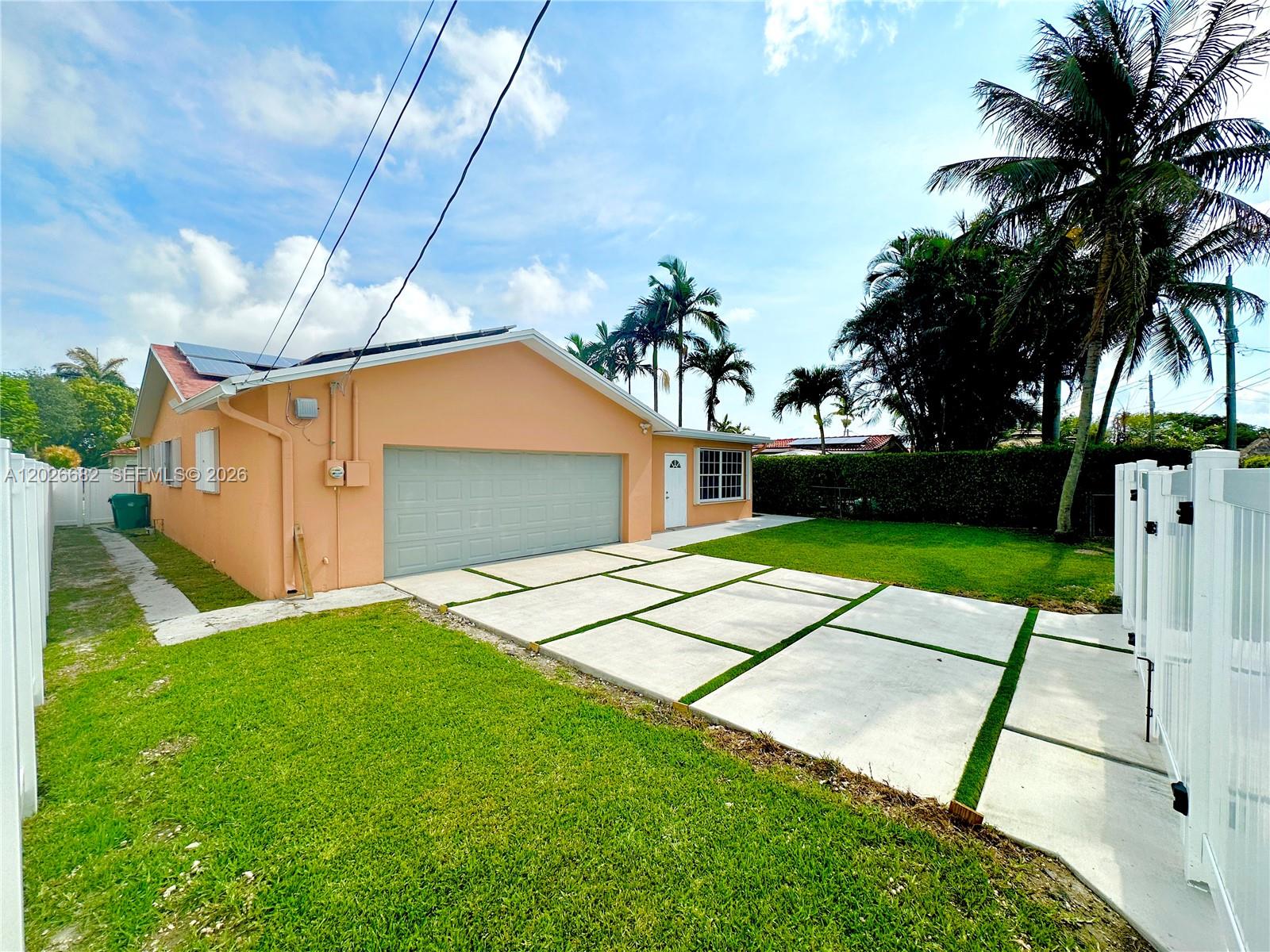 A peach-colored house features a gray garage door and a concrete paver driveway — 206 SE 3rd Pl, Dania Beach FL 33004, DANIA BEACH, FL