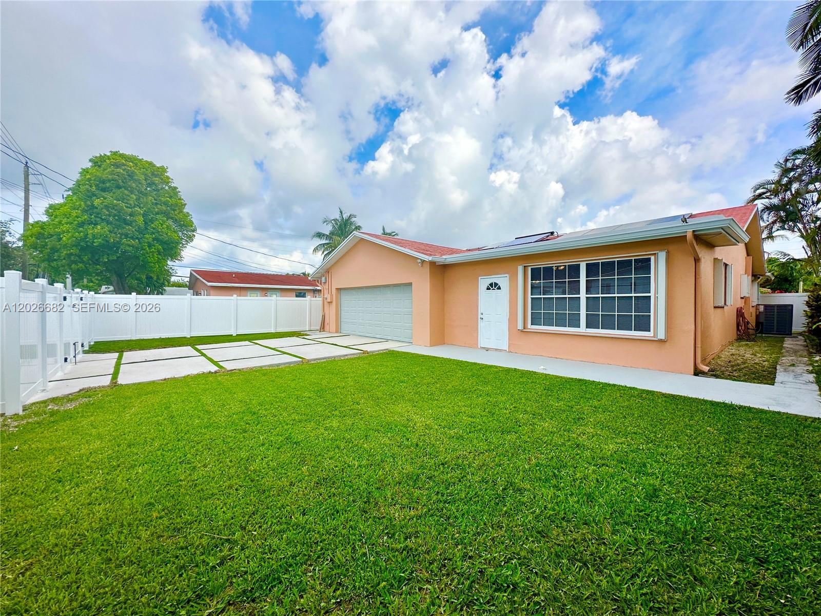 A peach-colored house features a white garage door, a front door, and a paved driveway — 206 SE 3rd Pl, Dania Beach FL 33004, DANIA BEACH, FL