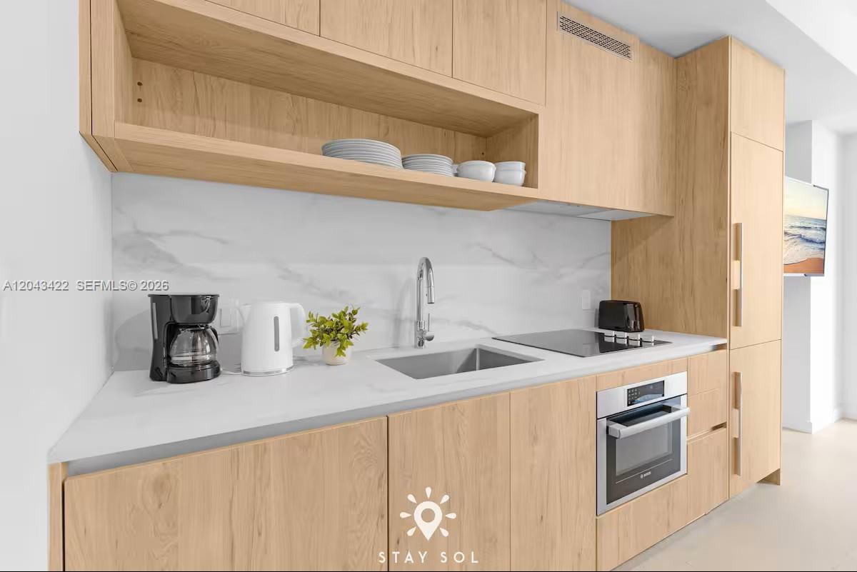 This is a rendering of a modern kitchen with light wood cabinetry and white countertops — 11 NE 6th St # 1606, Miami FL 33132, MIAMI, FL