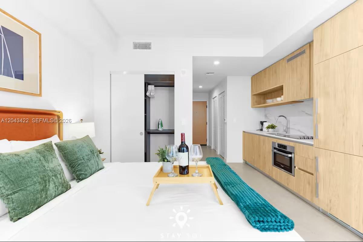 A studio apartment features a bed, a small kitchen area, and light wood cabinetry — 11 NE 6th St # 1606, Miami FL 33132, MIAMI, FL