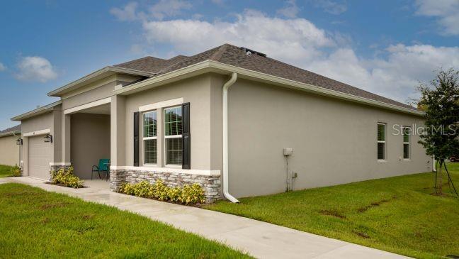 A covered front porch with a stone base, a black front door, and two chairs — 2631 FAIRFAX AVENUE, NEW SMYRNA BEACH, FL