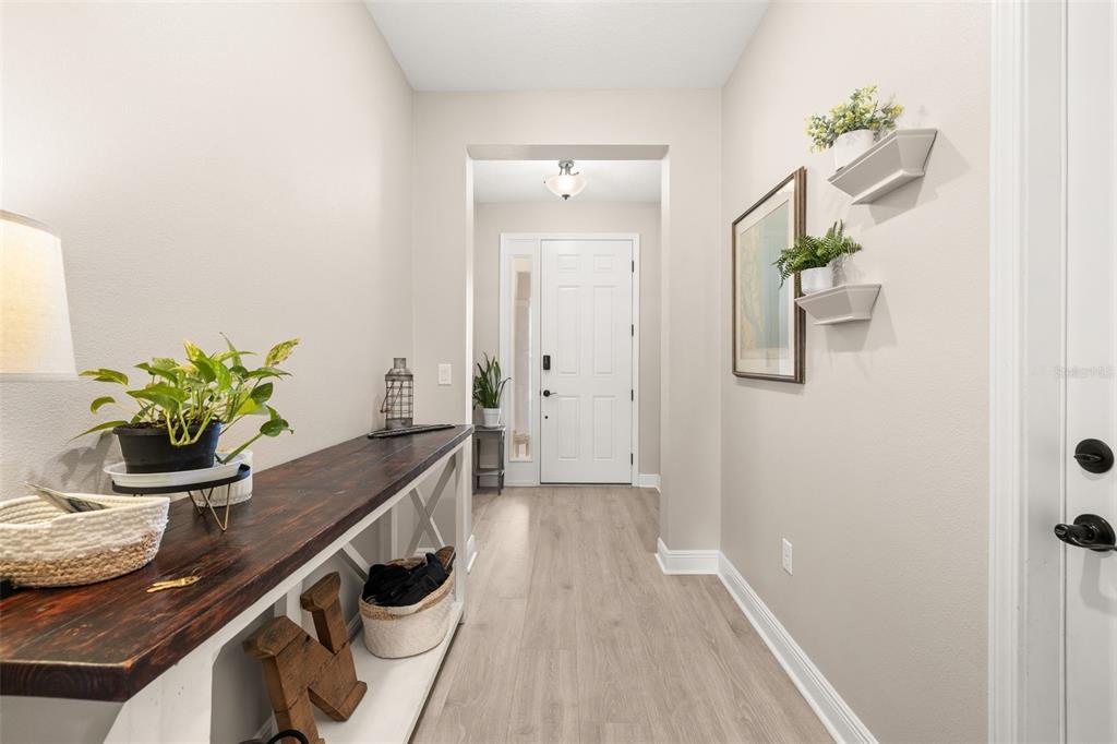 A bright entryway features light wood-look flooring, a rustic console table, and white trim — 4542 LIONS GATE AVENUE, CLERMONT, FL