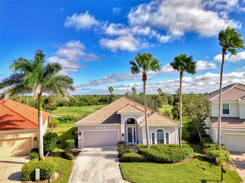 An exterior view of a single-story house with a tile roof, garage, and palm trees — 13384 GOLF POINTE DRIVE, PORT CHARLOTTE, FL