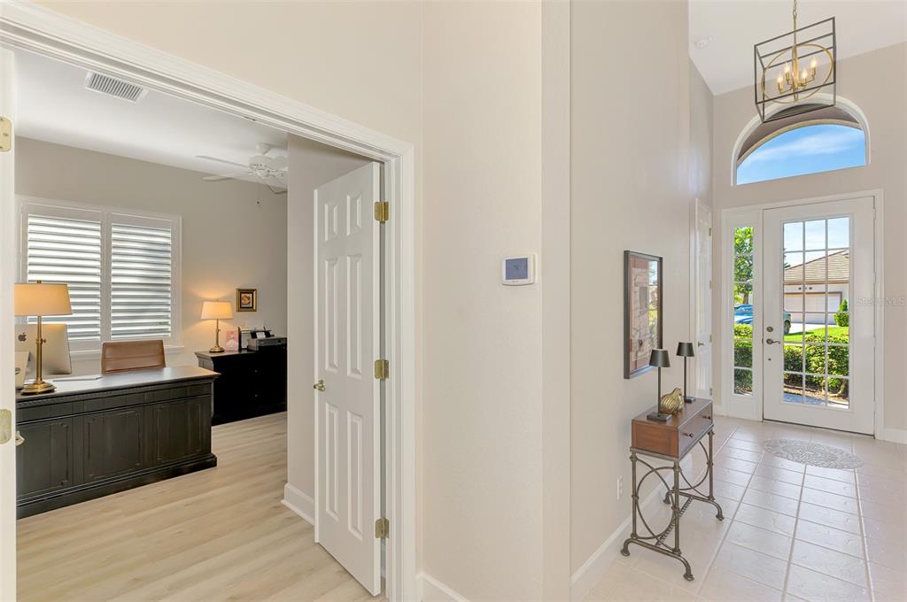 An entryway with tile flooring leads to a home office with a desk and shutters — 13384 GOLF POINTE DRIVE, PORT CHARLOTTE, FL