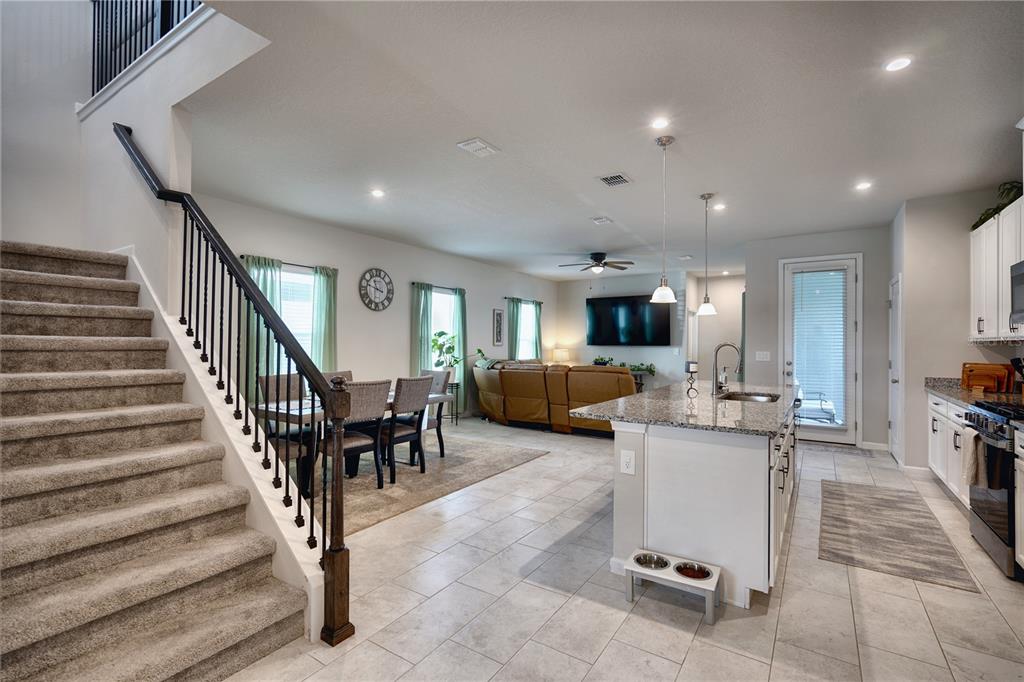 An open-concept living area features a carpeted staircase, a dining space, and a kitchen island — 3922 GREAT SMOKEY WAY, APOPKA, FL