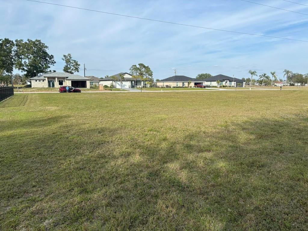 A large, grassy vacant lot is situated in front of several suburban houses — 25251 DOREDO DRIVE, PUNTA GORDA, FL