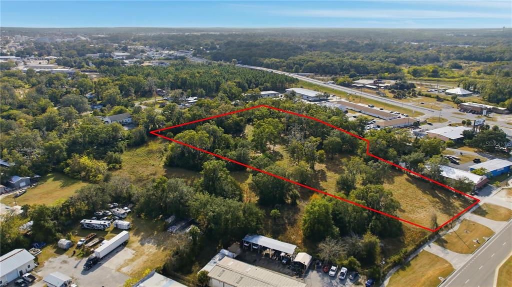 An aerial view shows a vacant, wooded lot outlined in red next to a road — TBD NW 20TH STREET, OCALA, FL