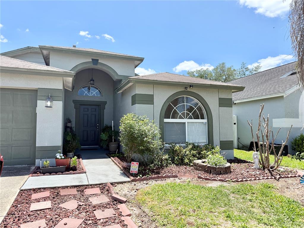 A single-story house with a beige exterior, a green garage door, and a vintage car parked outside — 30710 NICKERSON LOOP, WESLEY CHAPEL, FL