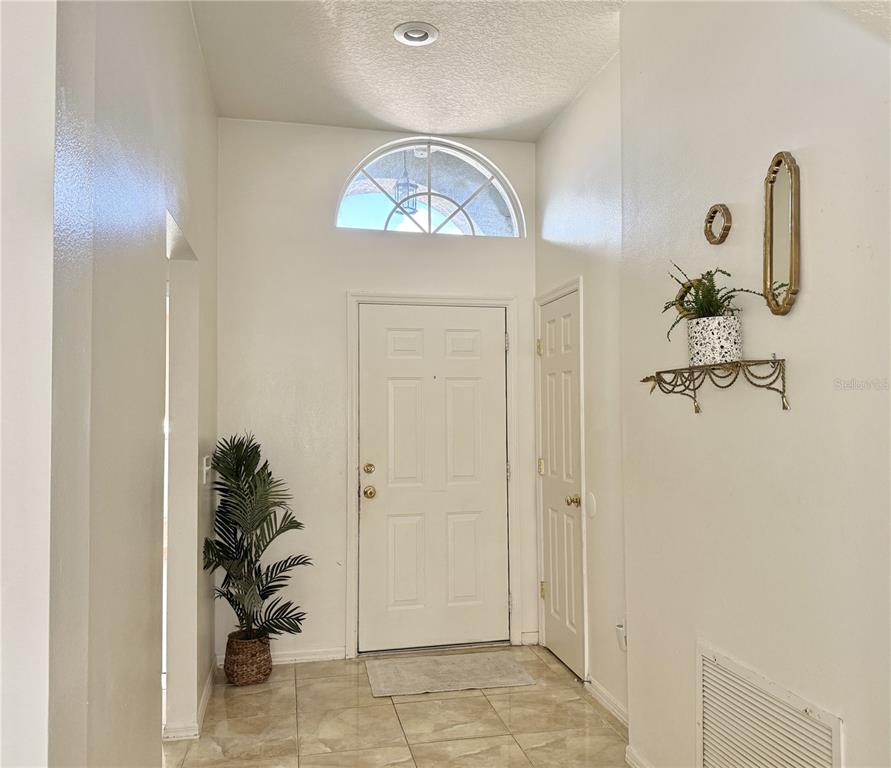 The exterior of a house features a covered entryway, a front door, and a large window — 30710 NICKERSON LOOP, WESLEY CHAPEL, FL
