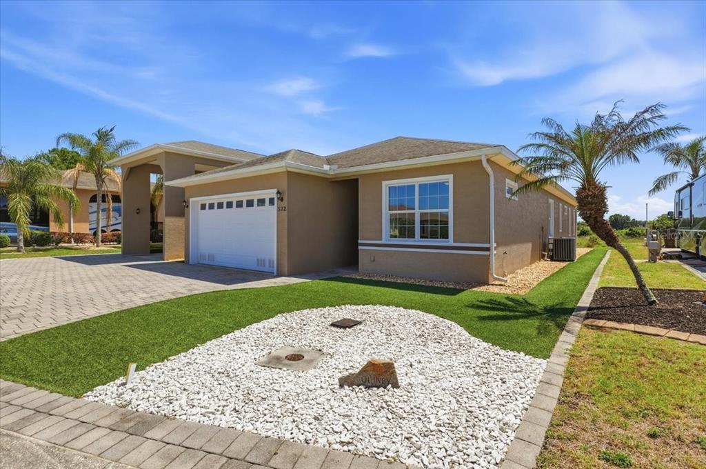 A tan single-story house with a white garage door and a white rock landscaping bed — 572 MEANDERING WAY, POLK CITY, FL