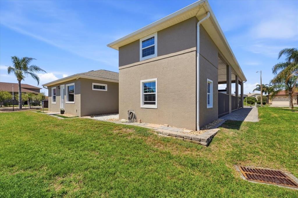 A two-story tan house exterior with white trim and a small adjacent single-story structure — 572 MEANDERING WAY, POLK CITY, FL
