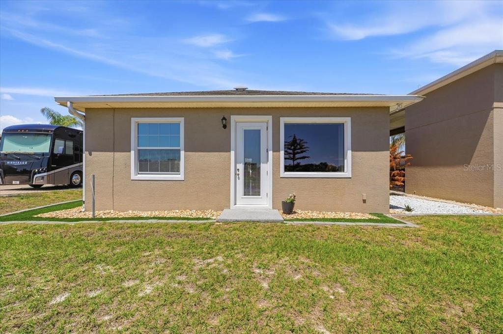 A tan, single-story exterior features a central glass-paneled door flanked by two windows — 572 MEANDERING WAY, POLK CITY, FL