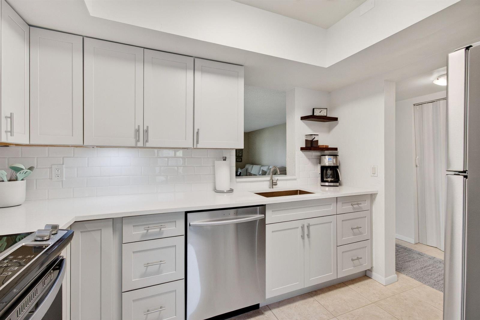 A modern kitchen features white cabinets, stainless steel appliances, and a subway tile backsplash — 6600 S Oriole Boulevard, Delray Beach FL 33446, DELRAY BEACH, FL