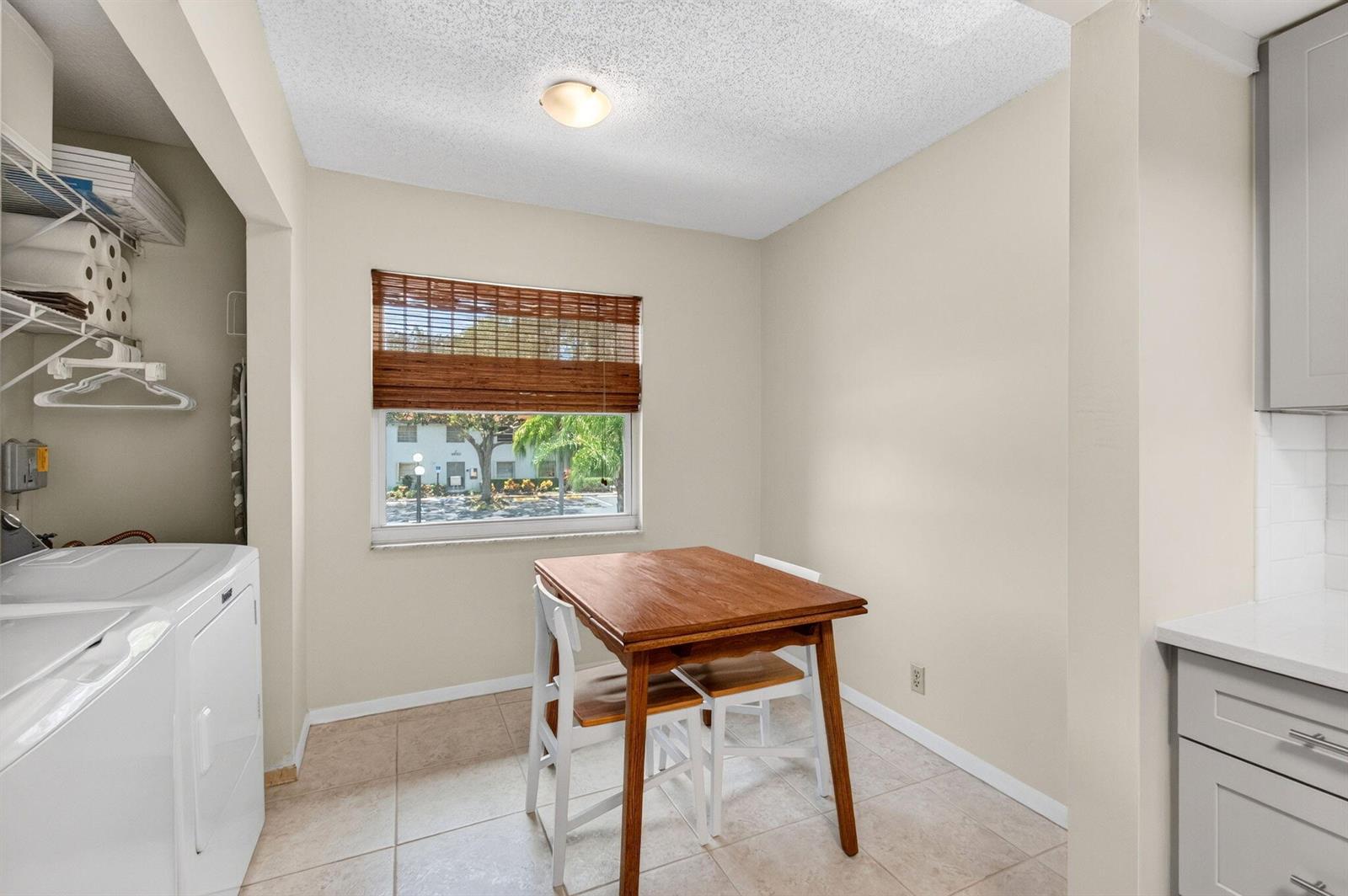 A dining area with a wooden table, two chairs, a window, and an adjacent laundry space — 6600 S Oriole Boulevard, Delray Beach FL 33446, DELRAY BEACH, FL