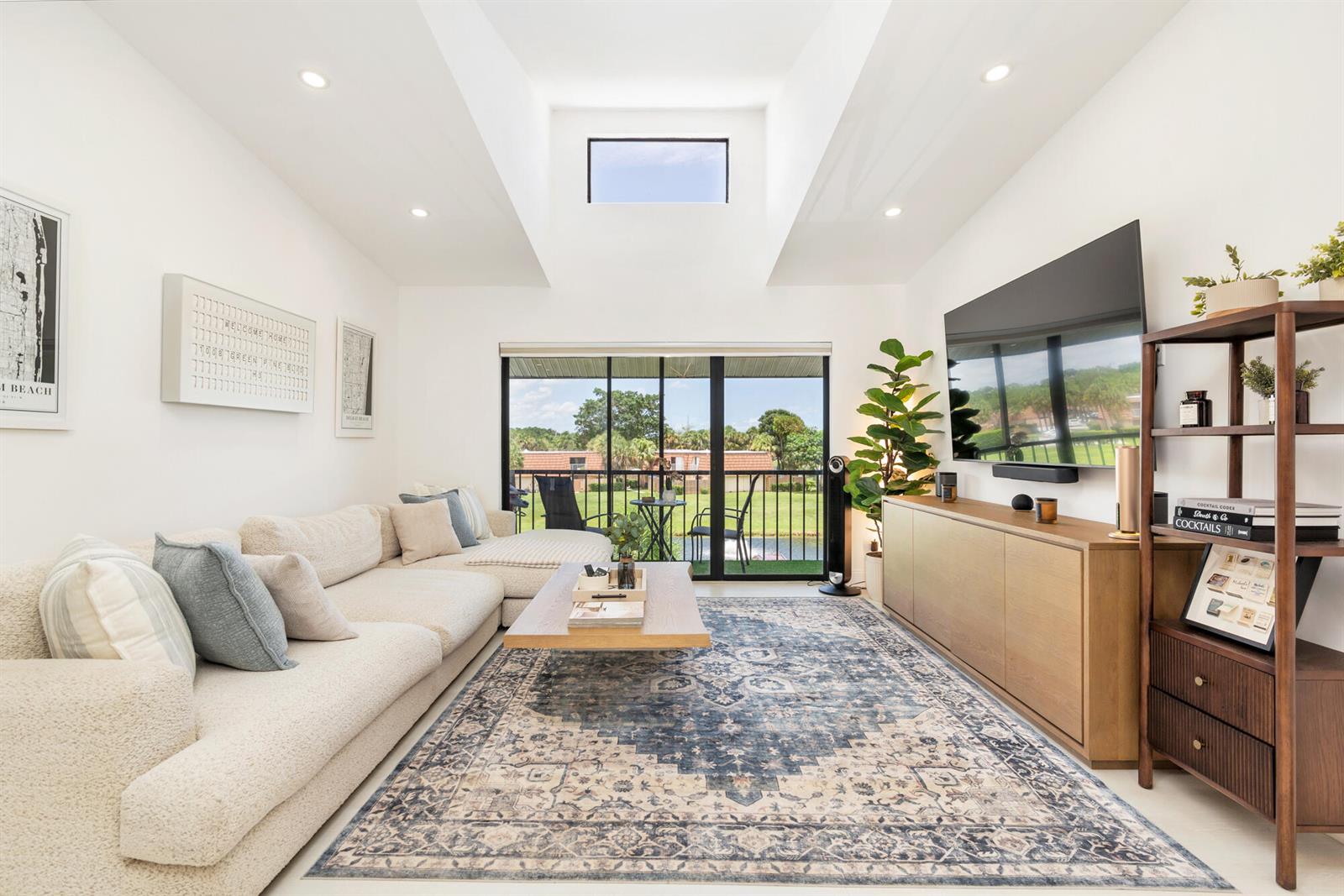 A bright living room features a vaulted ceiling, a large sectional sofa, and a sliding glass door — 1008 Green Pine Boulevard # H3, West Palm Beach FL 33409, WEST PALM BEACH, FL
