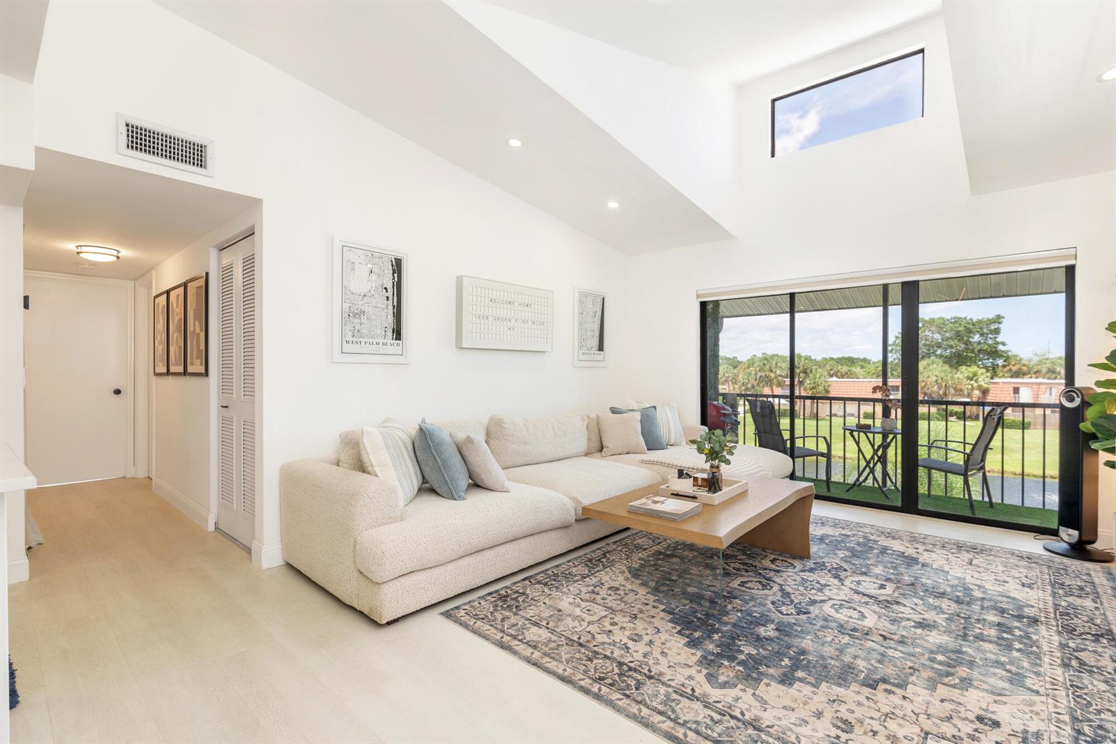 A bright living room features a cream sectional sofa, a patterned rug, and a balcony — 1008 Green Pine Boulevard # H3, West Palm Beach FL 33409, WEST PALM BEACH, FL