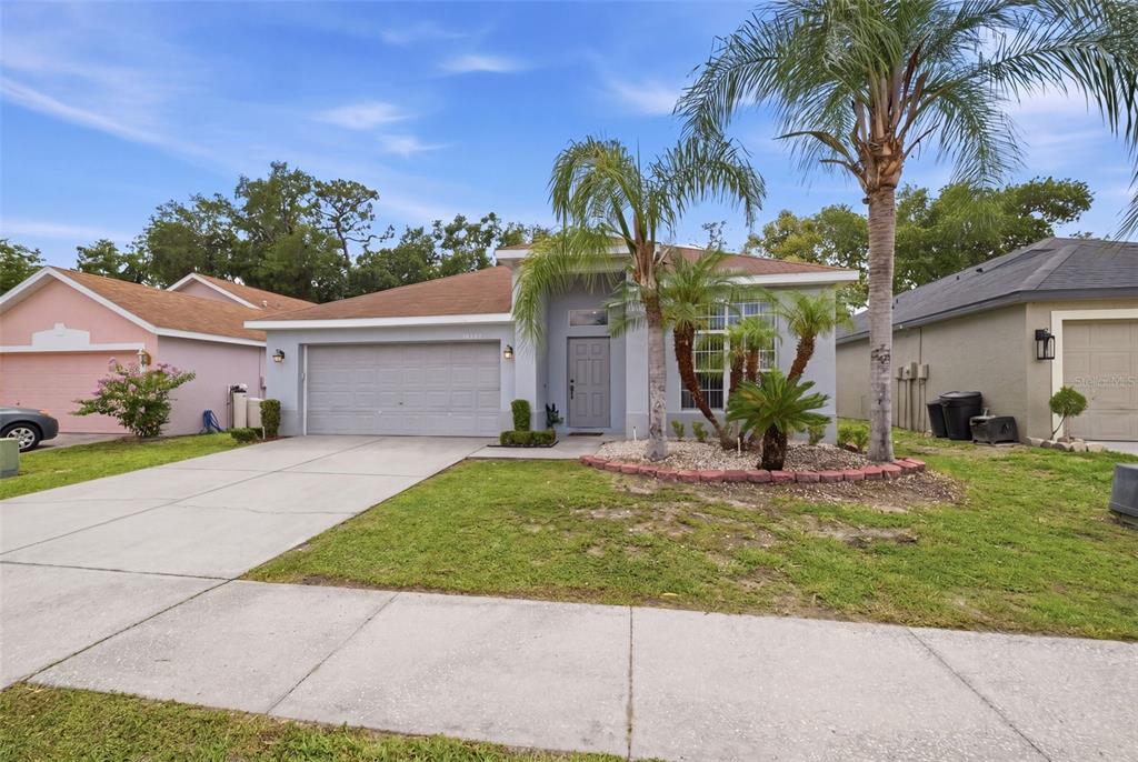 A single-story house with a gray exterior, a two-car garage, and a palm tree — 34507 SMART DRIVE, ZEPHYRHILLS, FL