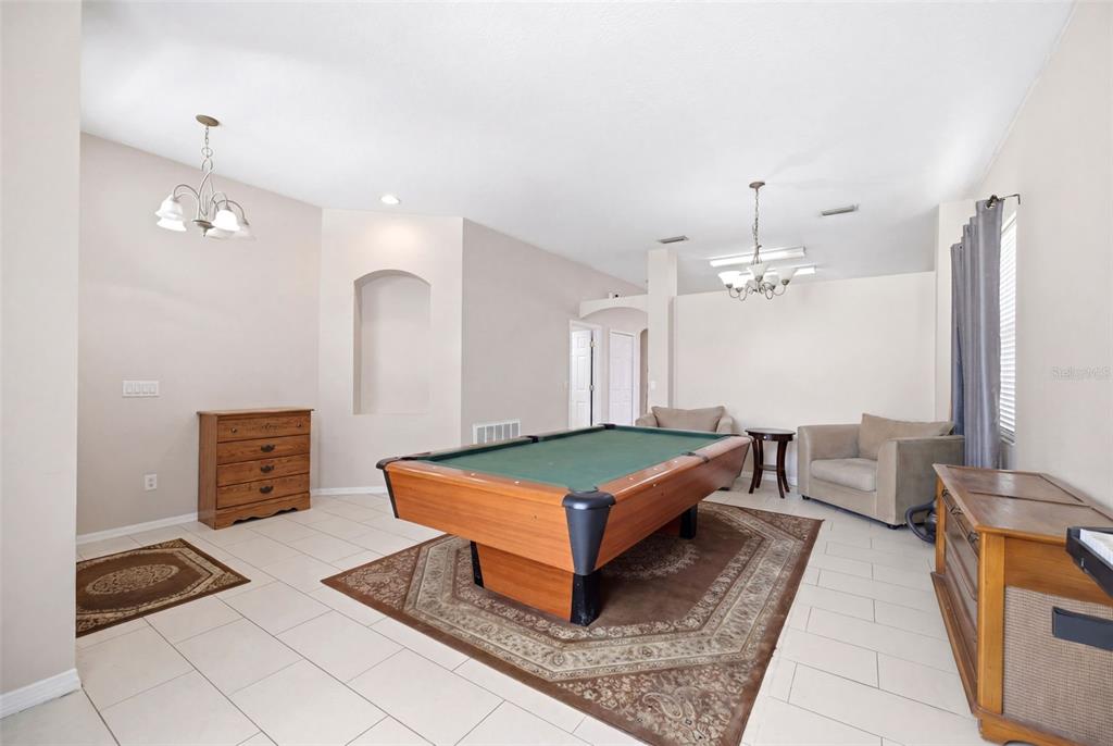 A game room features a pool table, tile flooring, two armchairs, and two wooden dressers — 34507 SMART DRIVE, ZEPHYRHILLS, FL