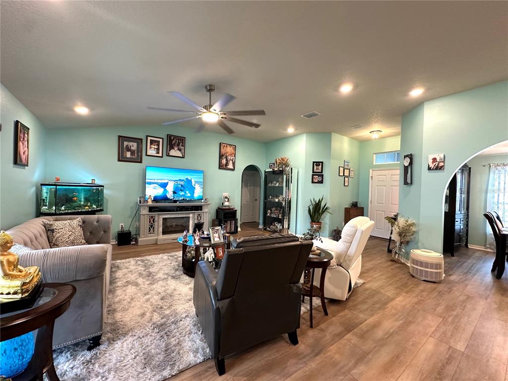 A living room features light blue walls, a gray sofa, a dark armchair, and a fireplace — 15329 SW 65TH TERRACE ROAD, OCALA, FL
