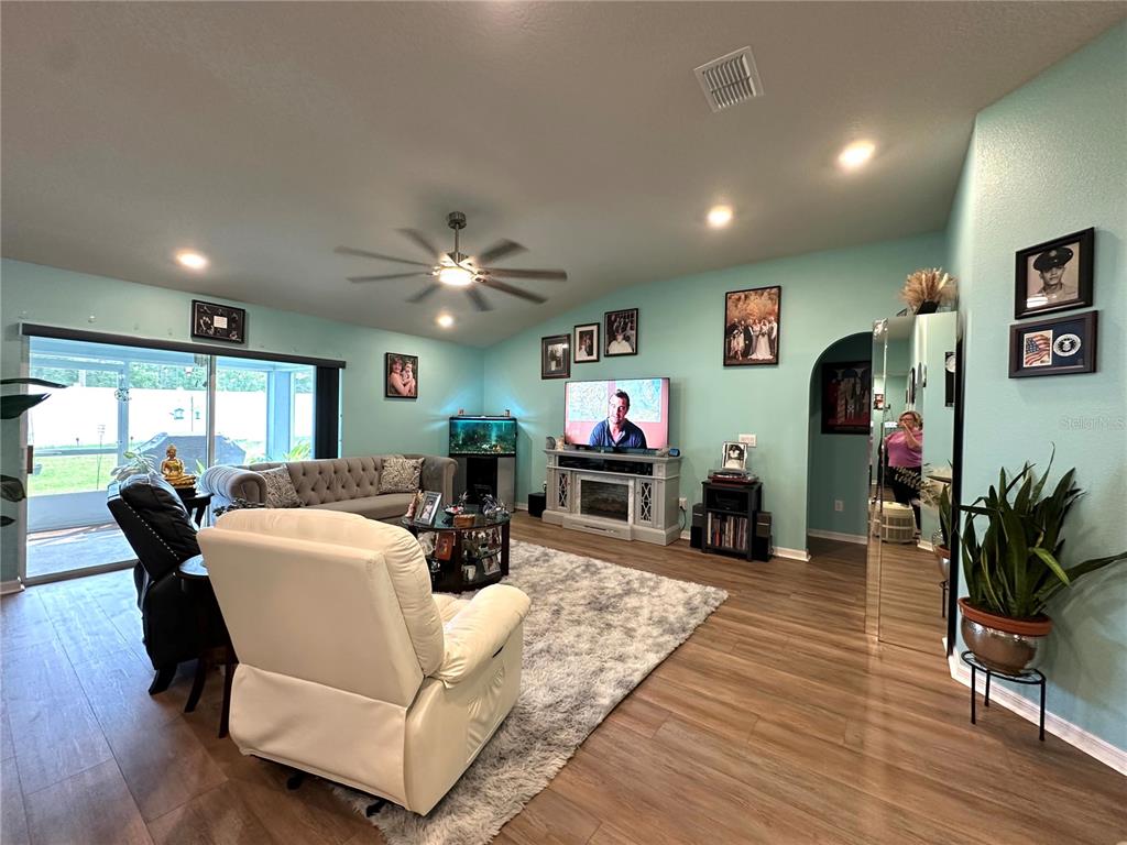 A living room features light blue walls, wood-look flooring, a fireplace console, and a rug — 15329 SW 65TH TERRACE ROAD, OCALA, FL