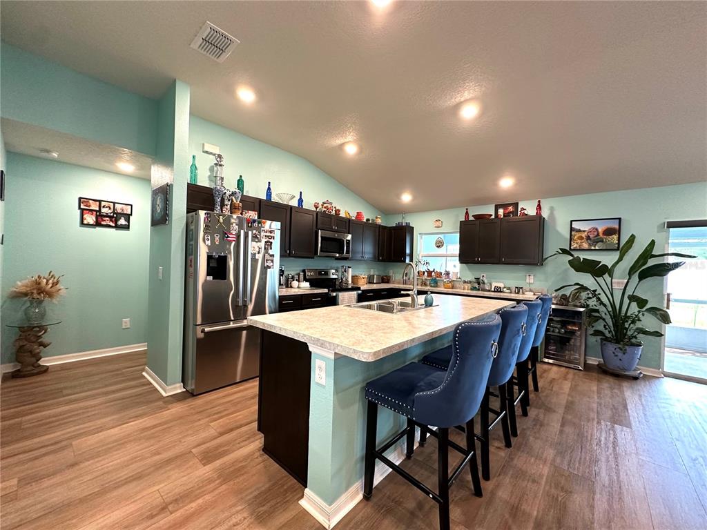A kitchen features dark cabinets, a central island with blue stools, and light-colored countertops — 15329 SW 65TH TERRACE ROAD, OCALA, FL