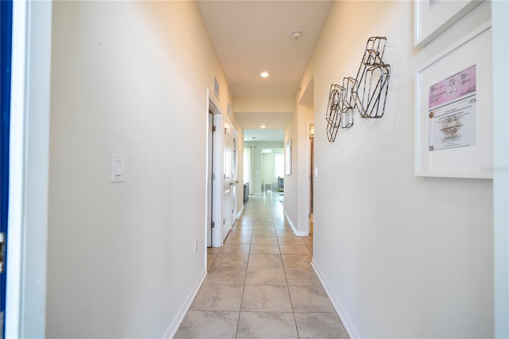 A long, tiled hallway leads toward an open living area with light-colored walls — 3121 PARADOX CIRCLE UNIT 303, KISSIMMEE, FL