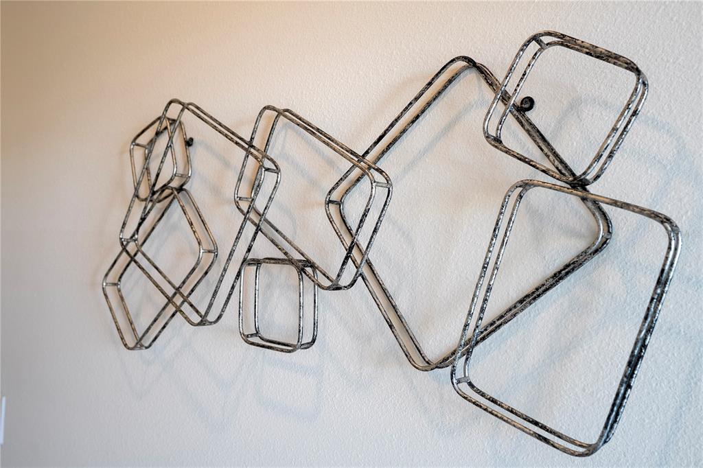 A modern, silver-toned geometric metal wall sculpture is mounted on a plain white wall — 3121 PARADOX CIRCLE UNIT 303, KISSIMMEE, FL
