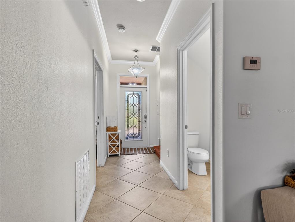 A tiled hallway leads to a front door with decorative glass and an adjacent bathroom — 2740 VIA PIAZZA LOOP, FORT MYERS, FL