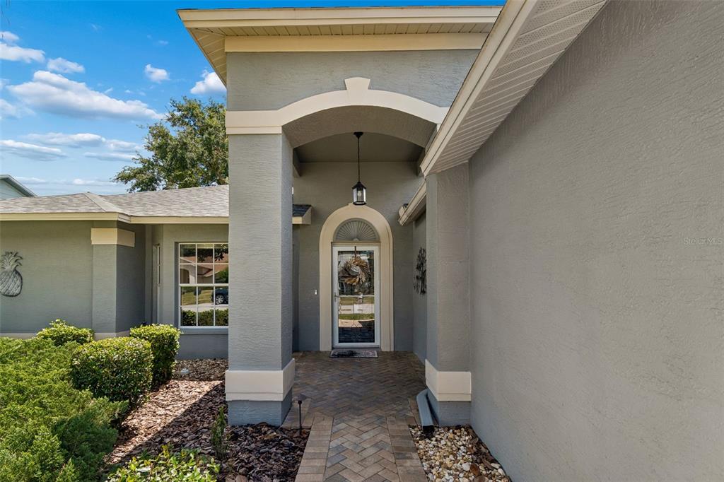 The exterior of a house features a covered entryway with a brick walkway and door — 18508 GRAND CLUB DRIVE, HUDSON, FL
