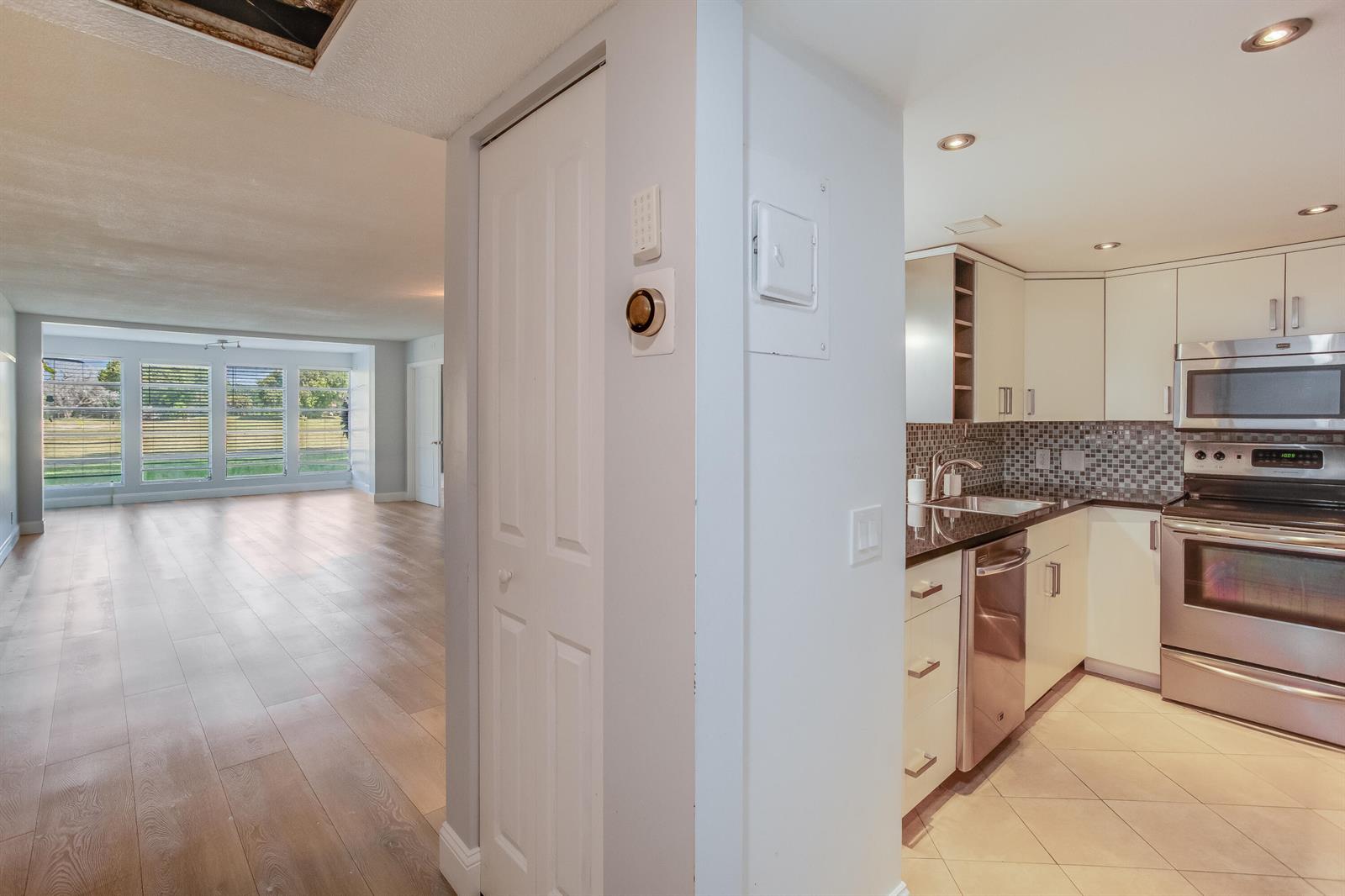 A kitchen with stainless steel appliances and tile floors opens to a living area — 2651 S Course Drive # 109, Pompano Beach FL 33069, POMPANO BEACH, FL