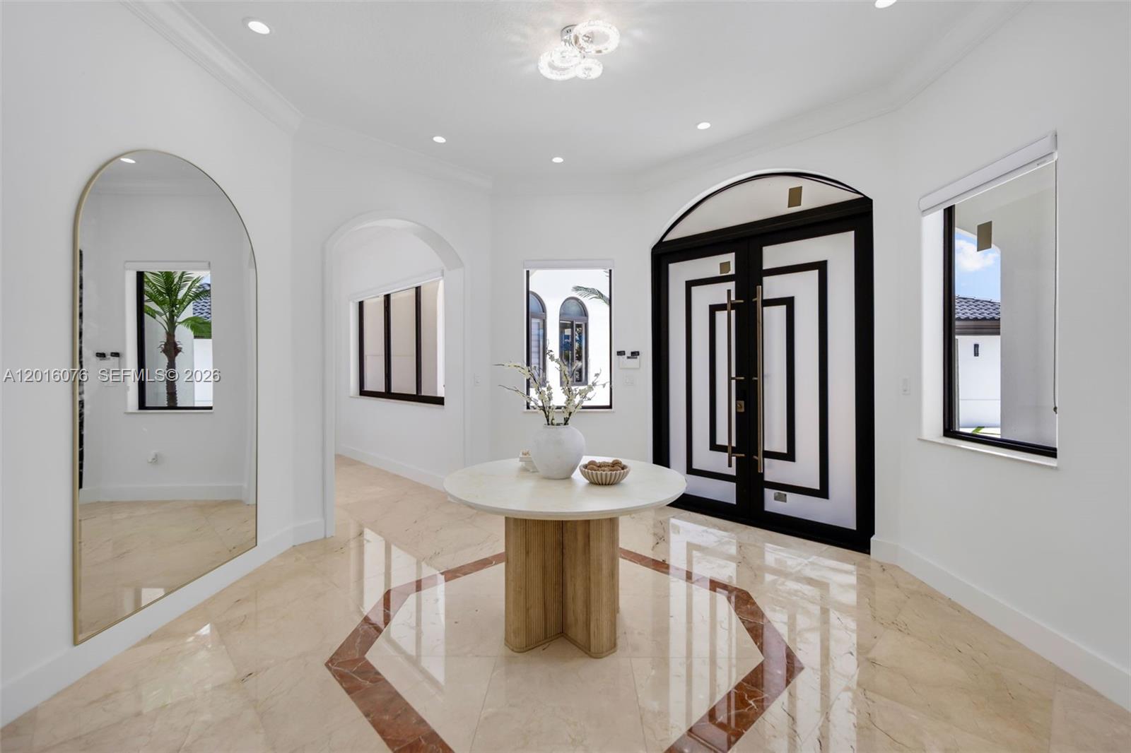 A bright foyer features marble floors with a geometric inlay, a round table, and arched mirror — 9881 SW 148th Ter, Miami FL 33176, MIAMI, FL