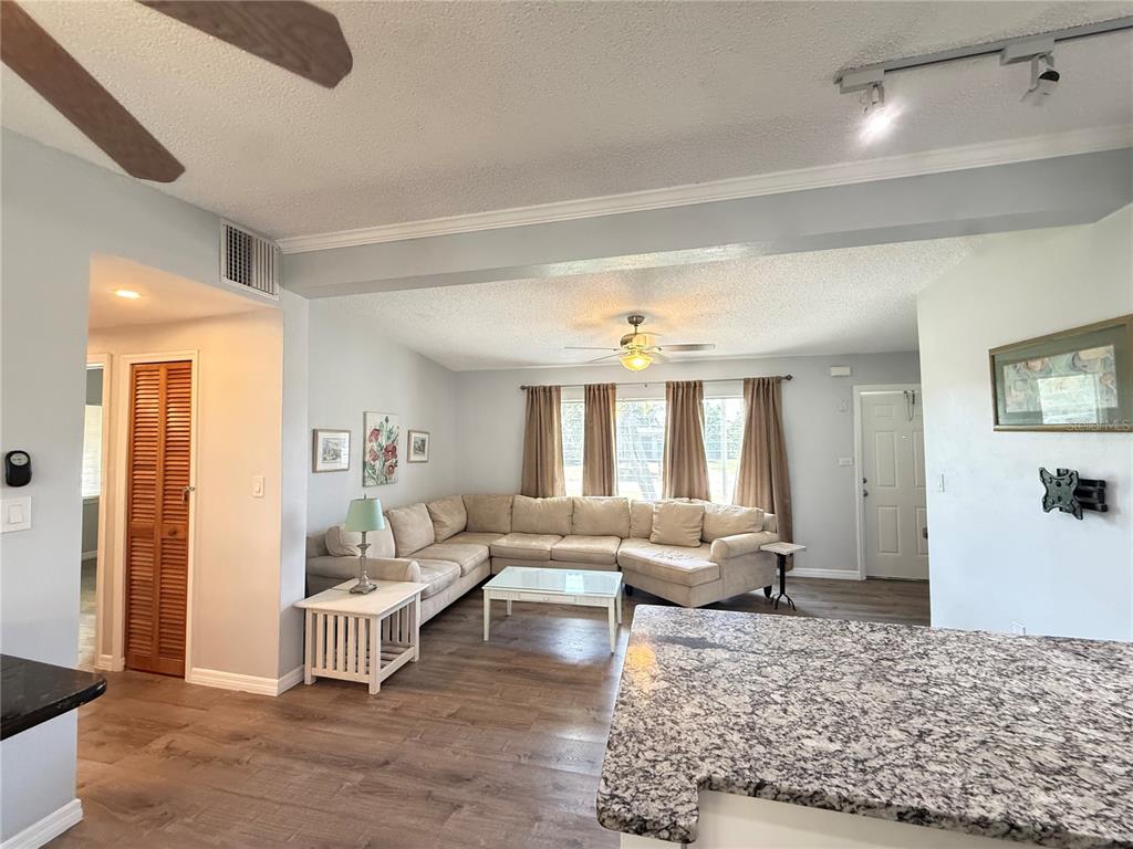 A living room features a large sectional sofa, wood-look flooring, and an open kitchen counter — 351 PALMETTO DRIVE NE, PORT CHARLOTTE, FL
