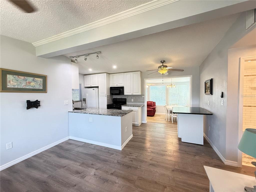 A kitchen with white cabinets, granite countertops, and a peninsula opens to a dining area — 351 PALMETTO DRIVE NE, PORT CHARLOTTE, FL
