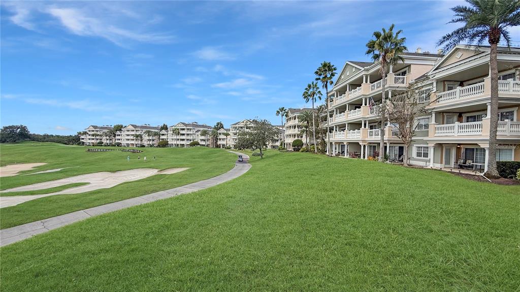A multi-story apartment complex overlooks a green golf course with sand traps and palm trees — 1370 CENTRE COURT RIDGE DRIVE UNIT 303, REUNION, FL
