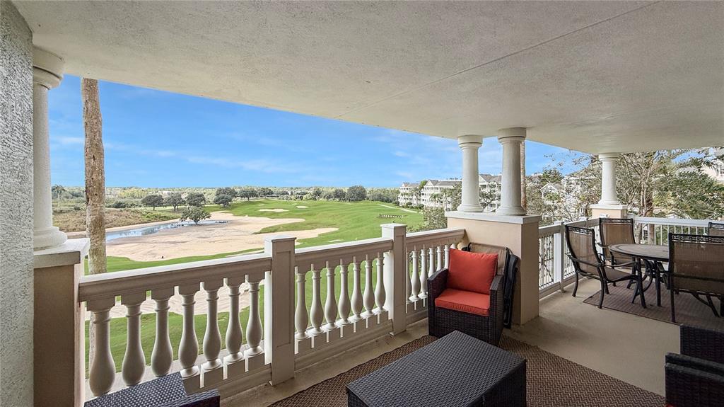 A covered balcony features a balustrade railing and outdoor furniture overlooking a golf course — 1370 CENTRE COURT RIDGE DRIVE UNIT 303, REUNION, FL