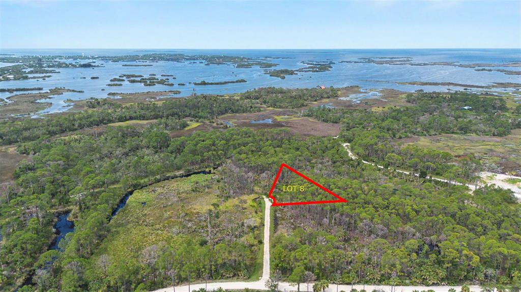 An aerial view shows a wooded lot outlined in red next to a paved road — Lot 8 SW 104 STREET, CEDAR KEY, FL
