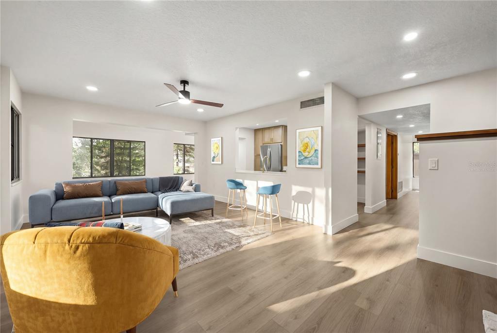 A living room with light wood floors, a blue sectional sofa, and a kitchen pass-through — 548 S OSCEOLA AVENUE, ORLANDO, FL