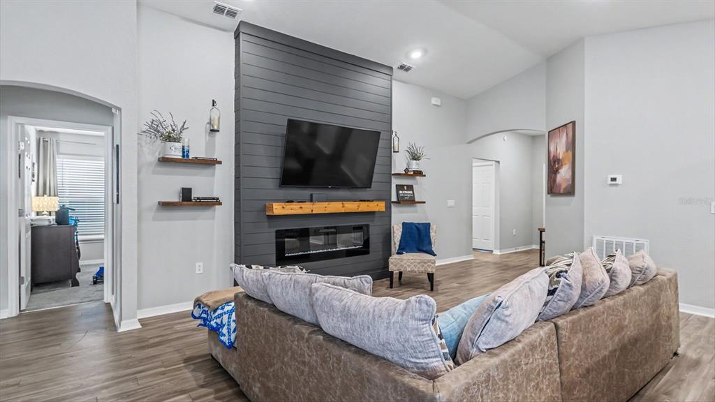 A living room features a dark gray shiplap fireplace wall with a mounted television — 1244 MEZZAVALLE WAY, AUBURNDALE, FL