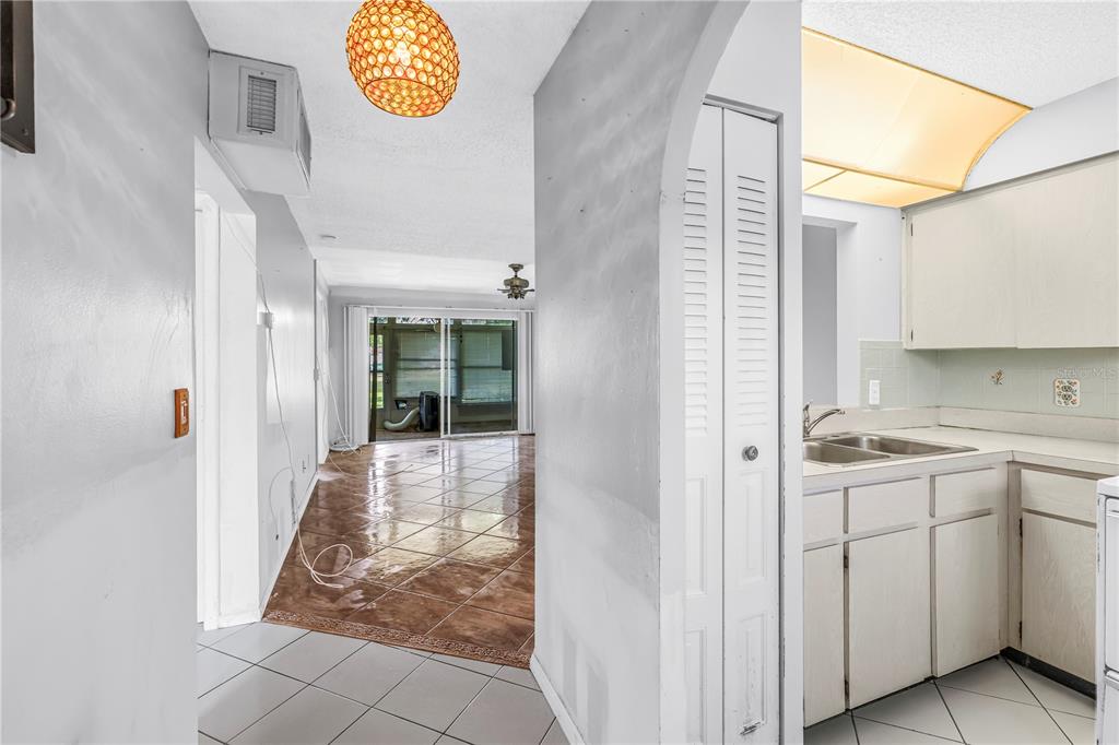 A view from a tiled kitchen looking toward a living area with a sliding glass door — 4774 LAKE BOULEVARD UNIT 9B, CLEARWATER, FL