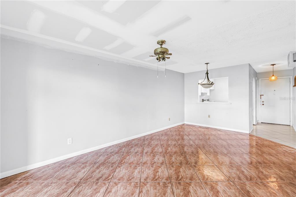 An empty living room features light gray walls, brown tile flooring, and a ceiling fan — 4774 LAKE BOULEVARD UNIT 9B, CLEARWATER, FL