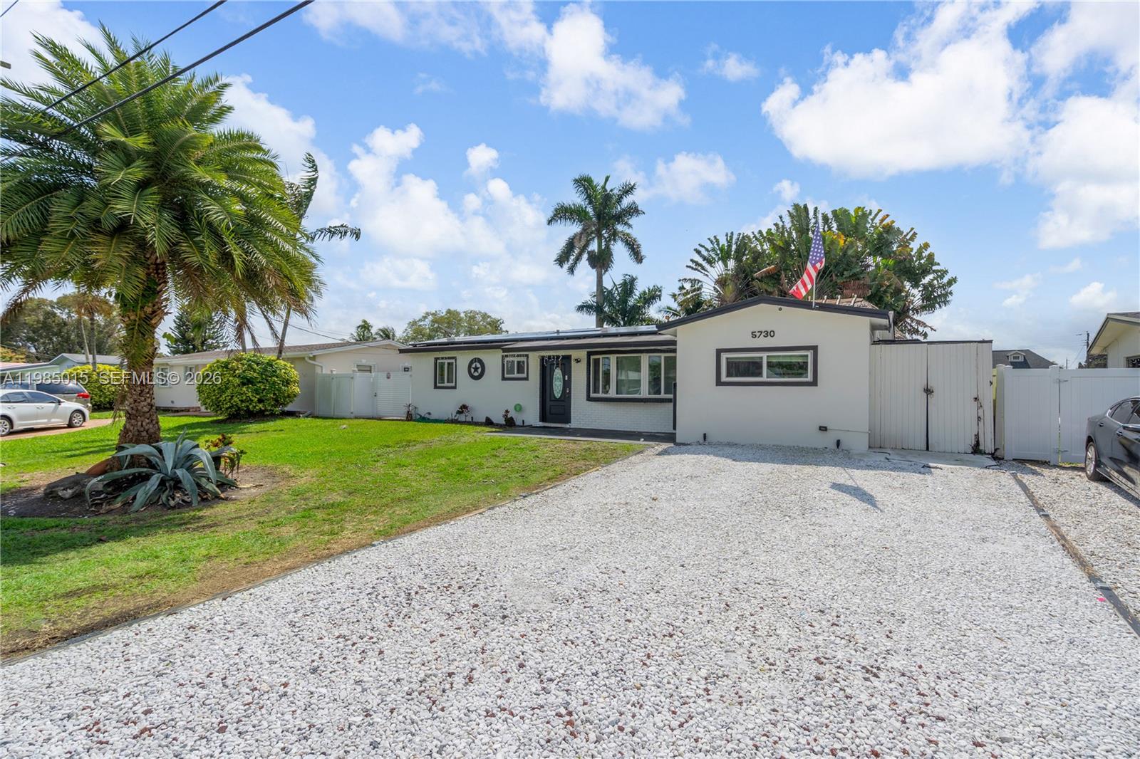 A single-story house features a white exterior, a gravel driveway, and a large palm tree — 5730 SW 55th St, Davie FL 33314, DAVIE, FL