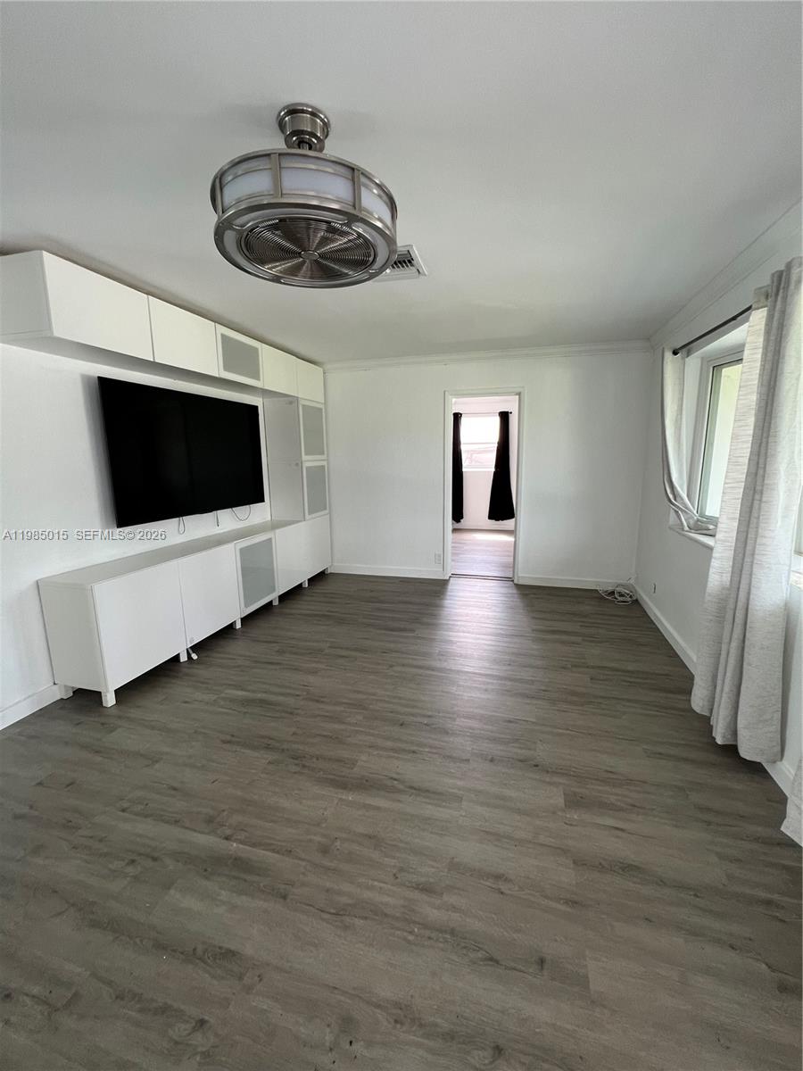 A living room features white built-in cabinetry, a wall-mounted television, and wood-look flooring — 5730 SW 55th St, Davie FL 33314, DAVIE, FL