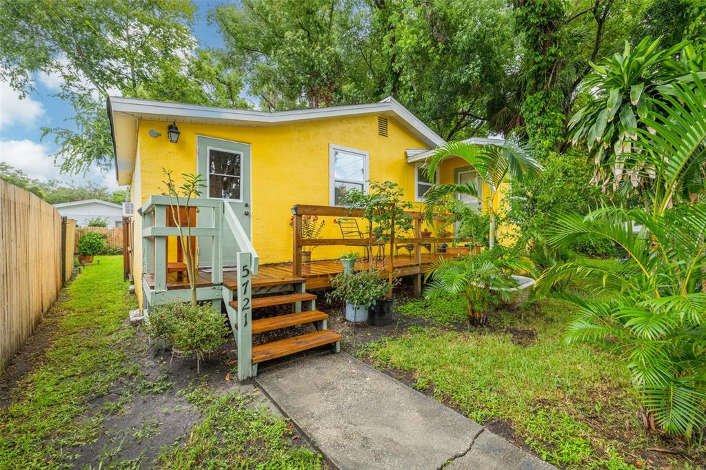 A bright yellow house features a wooden deck with stairs and a green railing — 5721 CASSON AVENUE, NEW PORT RICHEY, FL