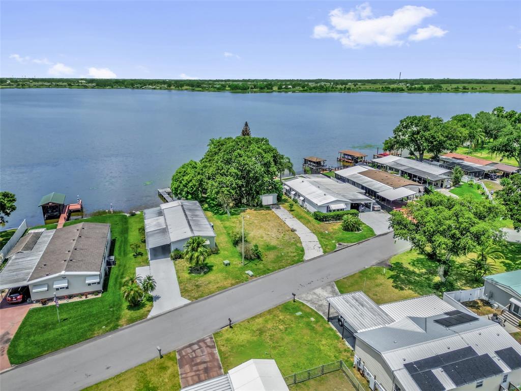 An aerial view shows several houses with carports situated along the shore of a lake — 2050 THELMA DRIVE, LAKE ALFRED, FL