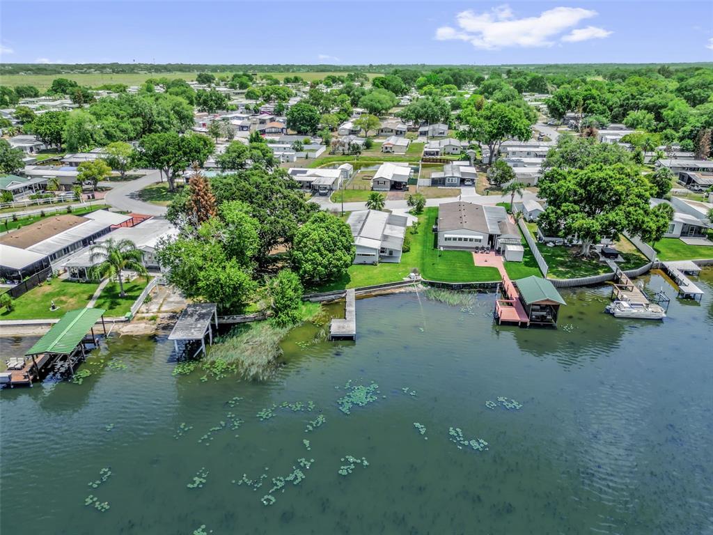 An aerial view shows waterfront homes with private docks along a lake in a neighborhood — 2050 THELMA DRIVE, LAKE ALFRED, FL