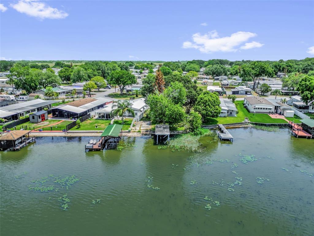An aerial view shows waterfront mobile homes with private docks along a green lake — 2050 THELMA DRIVE, LAKE ALFRED, FL