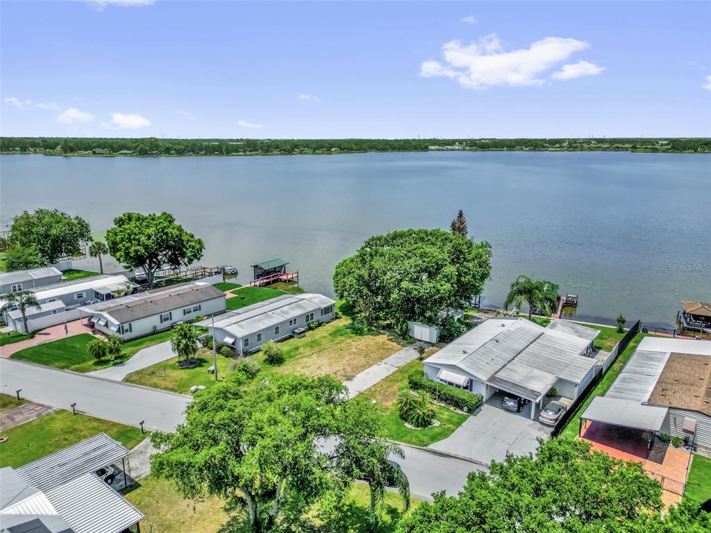 An aerial view shows several mobile homes situated along the edge of a large lake — 2050 THELMA DRIVE, LAKE ALFRED, FL