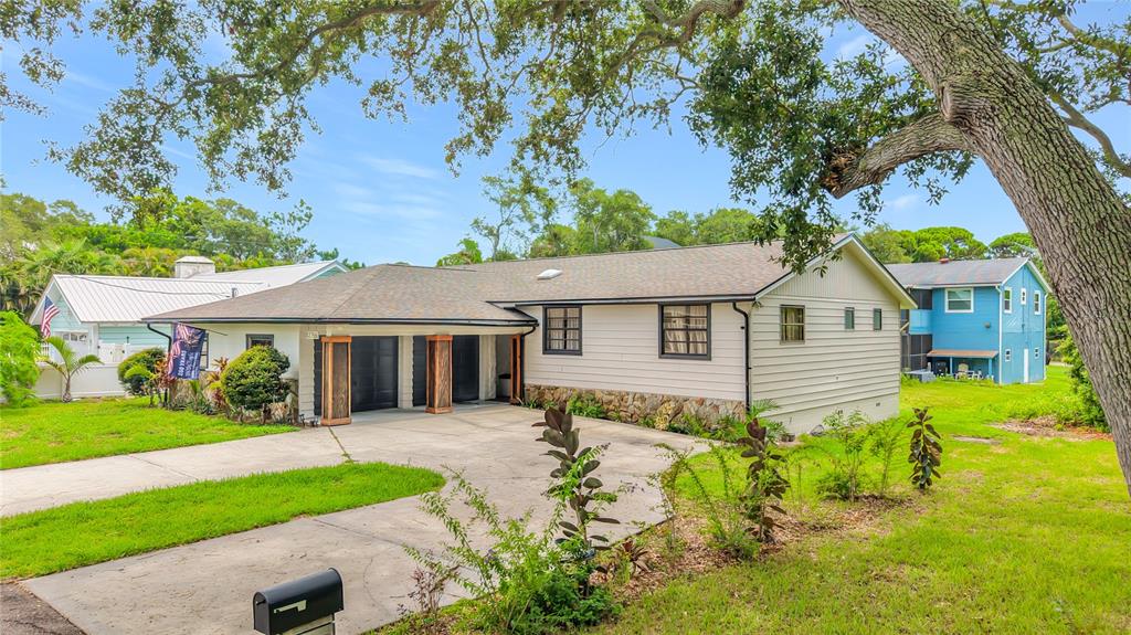 A single-story house with light siding, a stone base, and a concrete driveway — 12756 POINSETTIA AVENUE, SEMINOLE, FL