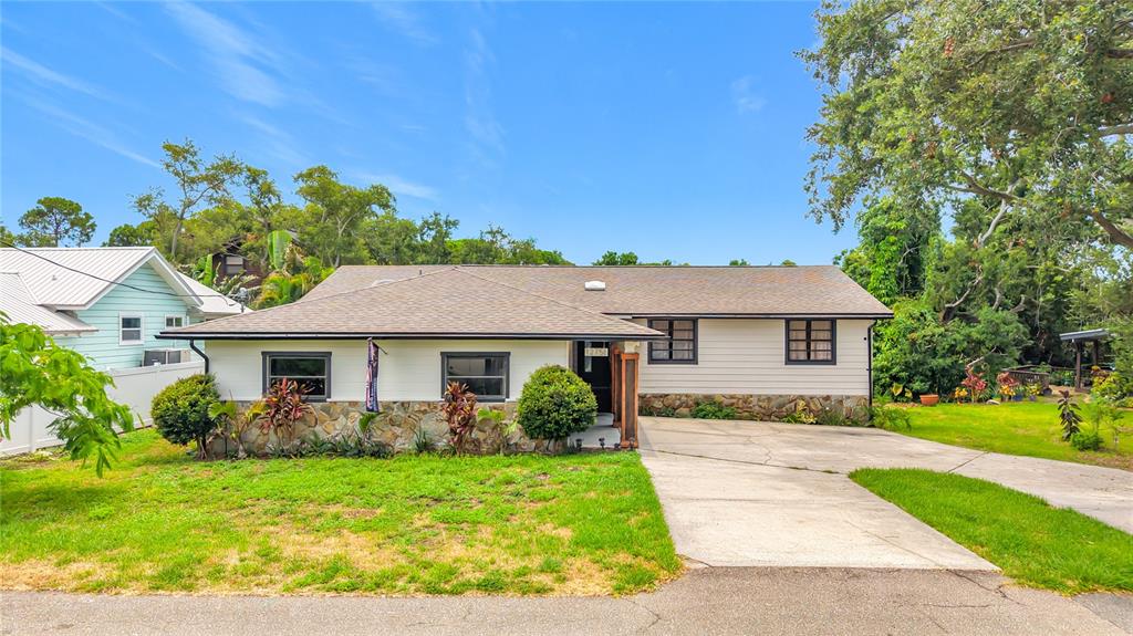 A single-story house with light siding, a stone base, and a concrete driveway — 12756 POINSETTIA AVENUE, SEMINOLE, FL