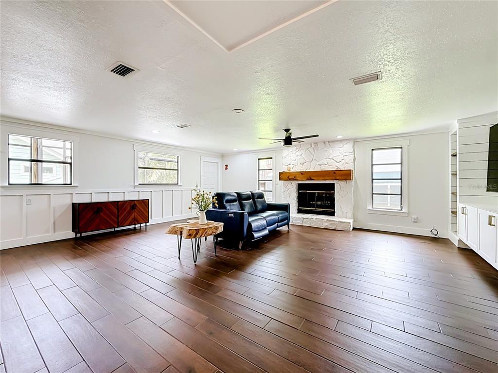 A living room features dark wood floors, a white stone fireplace, and a blue sofa — 12756 POINSETTIA AVENUE, SEMINOLE, FL
